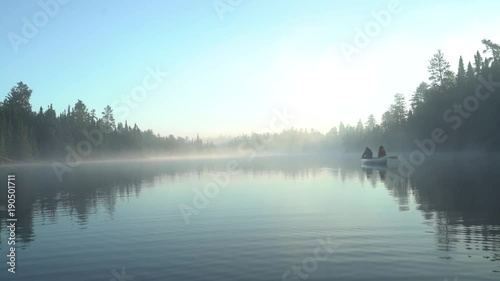 Rear view of people sitting in boat on lake against clear sky photo