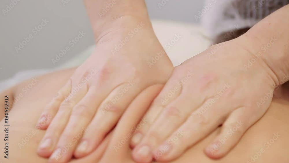 Close up. Masseuse carries out massages of the body, gently massaging his back in the beauty salon Close up. Masseuse carries out massages of the body, gently massaging his back in the beauty salon