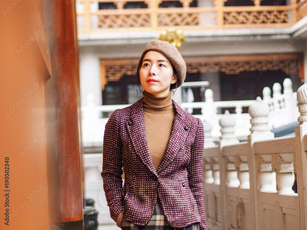 Beautiful young brunette woman with blur temple buildings background. Outdoor fashion portrait of glamour young Chinese cheerful stylish lady. Emotions, people, beauty and lifestyle concept. Beautiful young brunette woman with blur temple buildings background. Outdoor fashion portrait of glamour young Chinese cheerful stylish lady. Emotions, people, beauty and lifestyle concept.