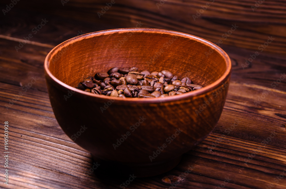 Roasted coffee beans in bowl on wooden table Roasted coffee beans in bowl on wooden table
