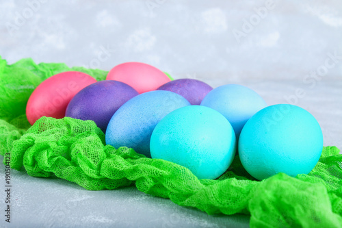 Colored Easter eggs on a green gauze on a gray concrete background.