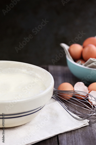 Bowl of homemade pancake batter mix with farm fresh brown eggs in background. Extreme shallow depth of field. Perfect for Shrove Tuesday.