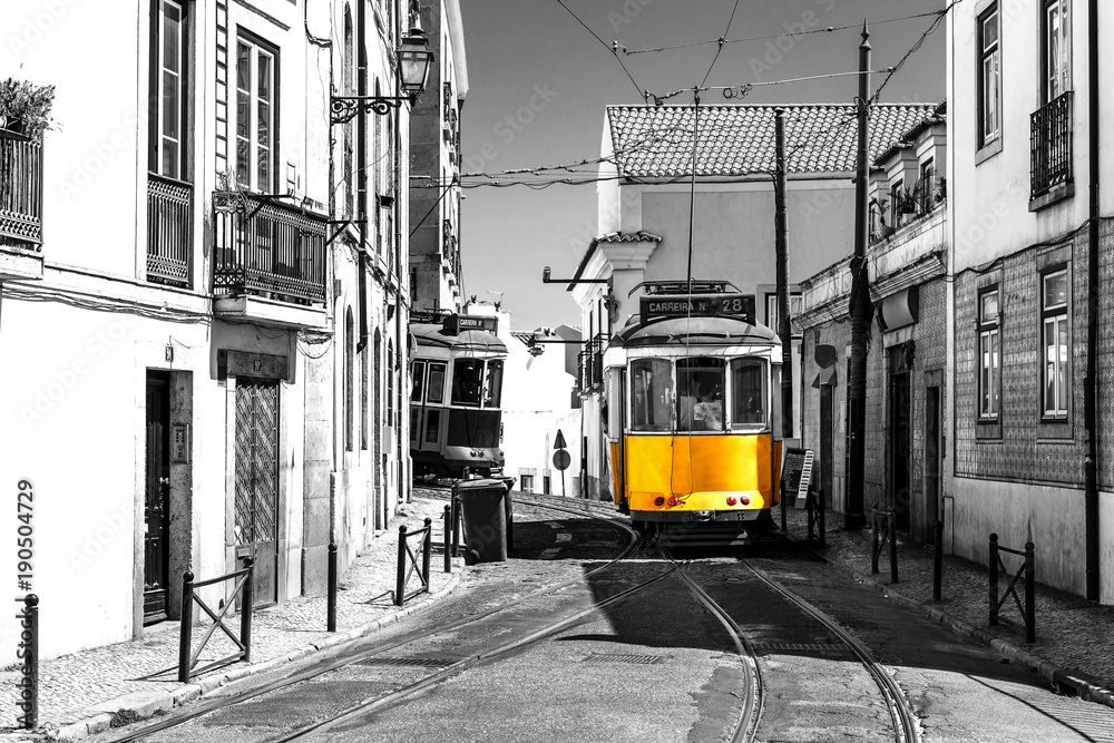 Yellow tram on old streets of Lisbon, Portugal, popular touristic attraction and destination. Black and white picture with a coloured tram.