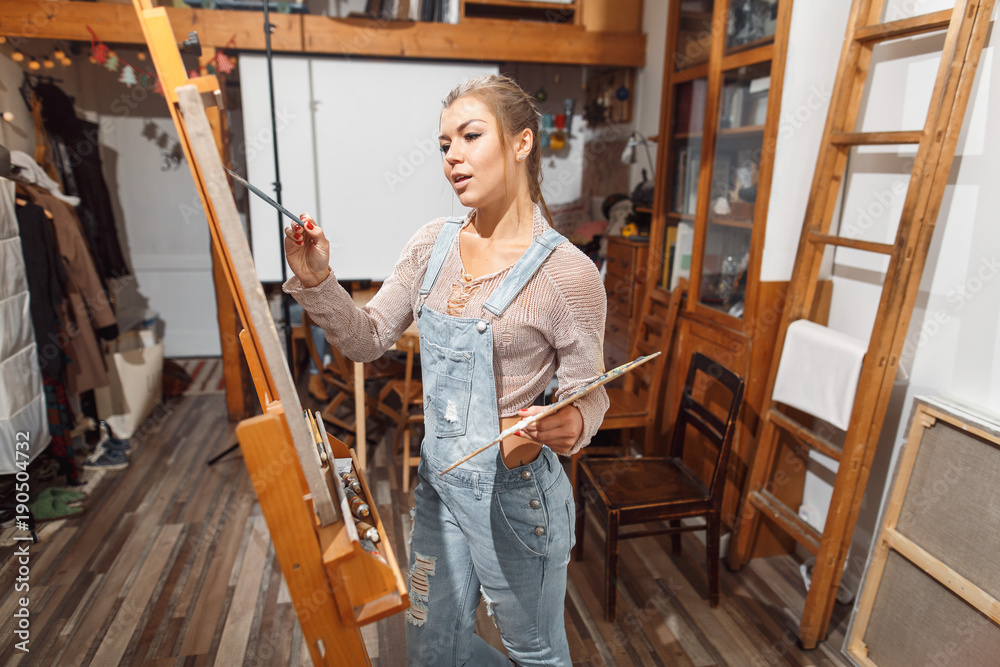 Smiling girl paints on canvas with oil colors in workshop Smiling girl paints on canvas with oil colors in workshop