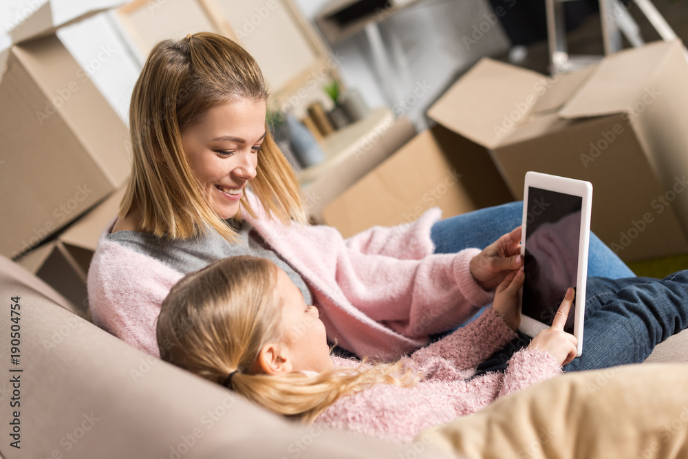happy mother and daughter using digital tablet with blank screen while moving home happy mother and daughter using digital tablet with blank screen while moving home