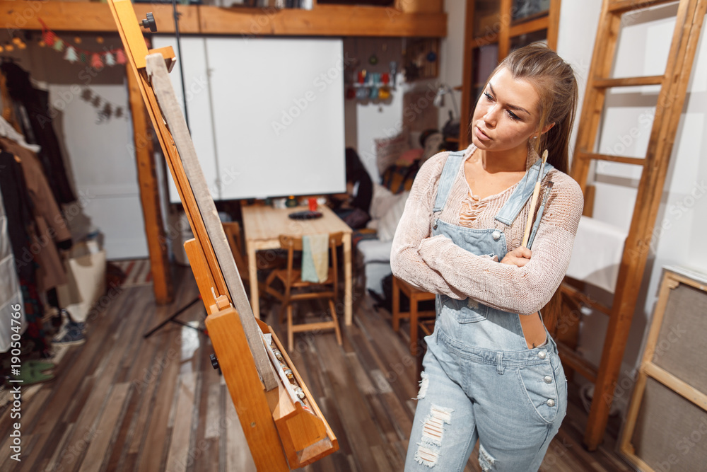 Smiling girl paints on canvas with oil colors in workshop Smiling girl paints on canvas with oil colors in workshop