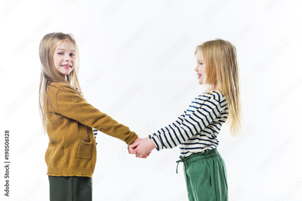 happy little sisters holding hands isolated on white happy little sisters holding hands isolated on white