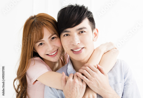 happy young asian couple hugging in living room