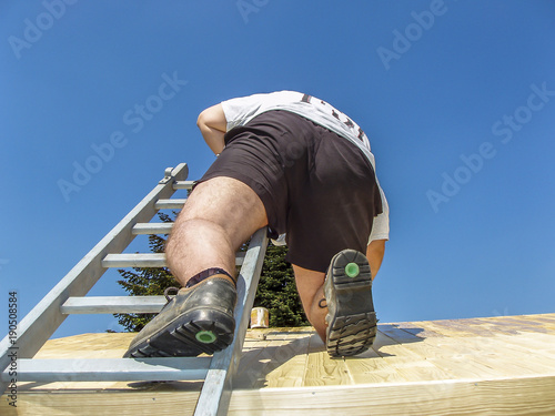 Man climbing on the roof and painting photo