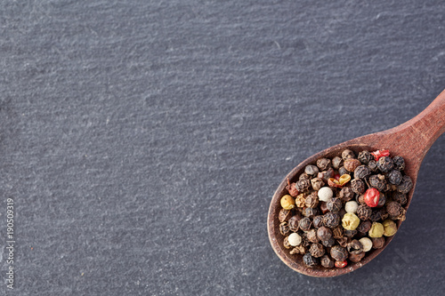 Chinese pepper, Sichuan pepper in wooden spoon on black slate stone plate