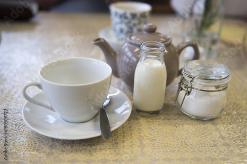 Cup and saucer with a teapot  milk and sugar  in a caf   setting