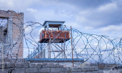 Historic brick prison wall showing guard tower and coiled barbed wire
