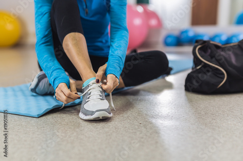 Woman tying shoelace before training in gym