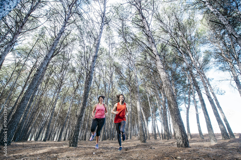 Fototapeta premium two beautiful women running through the forest