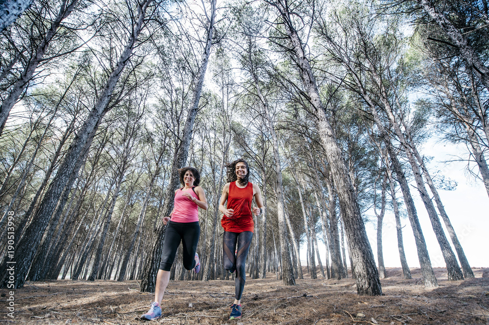 Fototapeta premium two beautiful women running through the forest