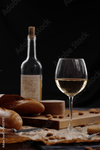 A glass of white wine on a table on a dark background. 