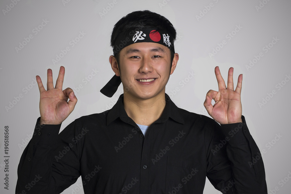 Retrato de un Asiatico con una bandana negra haciendo signo positivo. Retrato de un Asiatico con una bandana negra haciendo signo positivo.