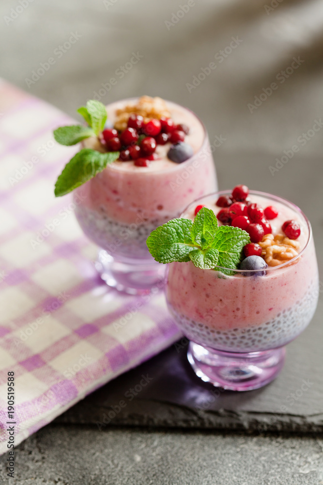 Layered chia, banana and berry smoothie garnished with fresh mint, healthy food style on black slate background Layered chia, banana and berry smoothie garnished with fresh mint, healthy food style on black slate background