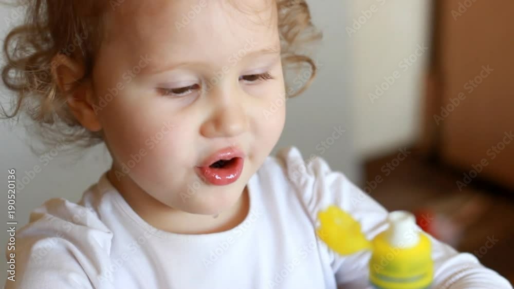 Funny cute little girl is drinking water from a bottle. Child and thirst. The baby takes a sip of the drink close up Funny cute little girl is drinking water from a bottle. Child and thirst. The baby takes a sip of the drink close up