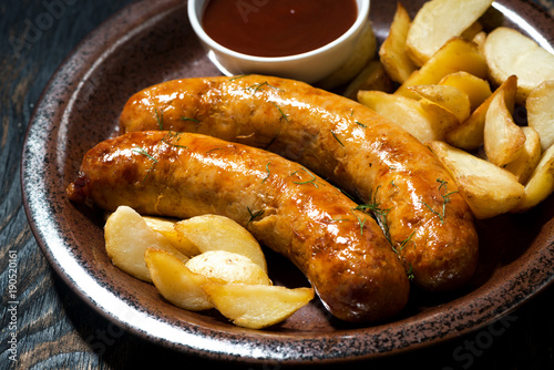fried pork sausages with potatoes and ketchup, closeup
