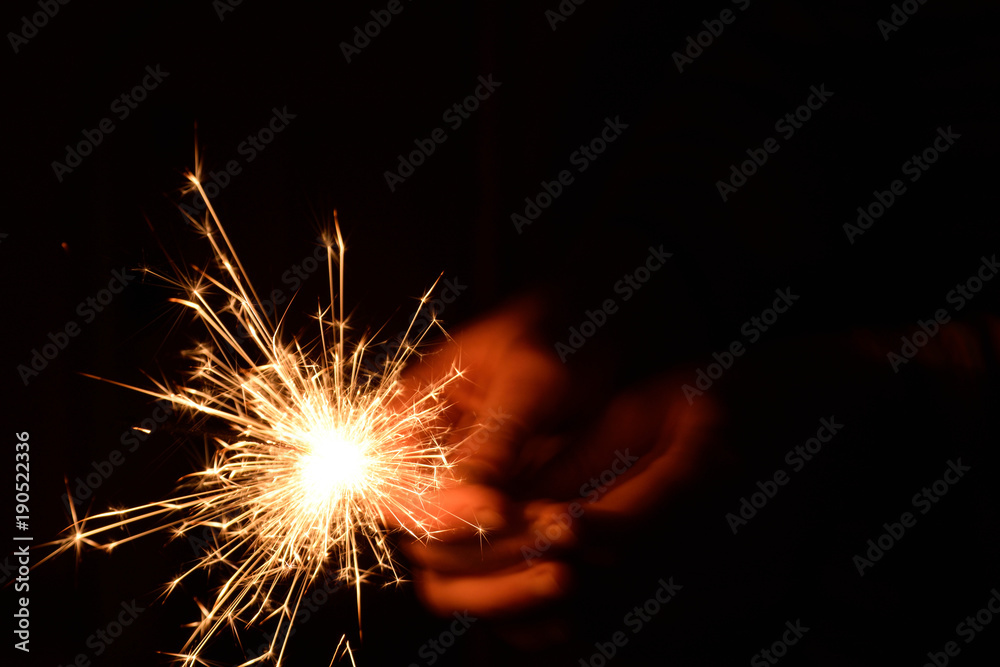 Blank background with bengal fire .Sparkler . New year party sparkler on black background A man holds a burning Bengal flame in his hands