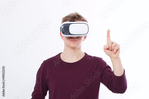 Young Man wearing virtual reality goggles and toch space by finger isolated on white background. VR concept and copy space. Selective focus. Blank template Shirt. © ladyalex