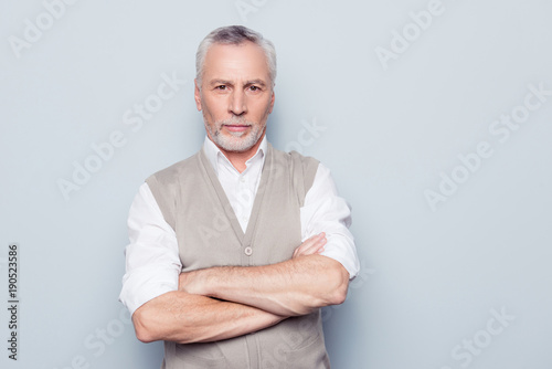 People individual lifestyle concept. Portrait of virile serious minded self-assured pensive granddad with crossed hands beige knitted waistcoat isolated on gray background copy-space