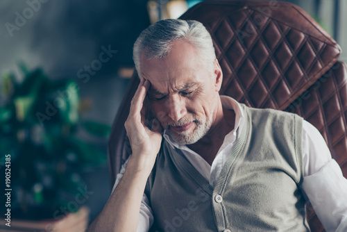 Close up portrait of sad upset nervous troubled problematic entrepreneur having strong headache wearing knitted waistcoat white shirt touching head temples with closed eyes