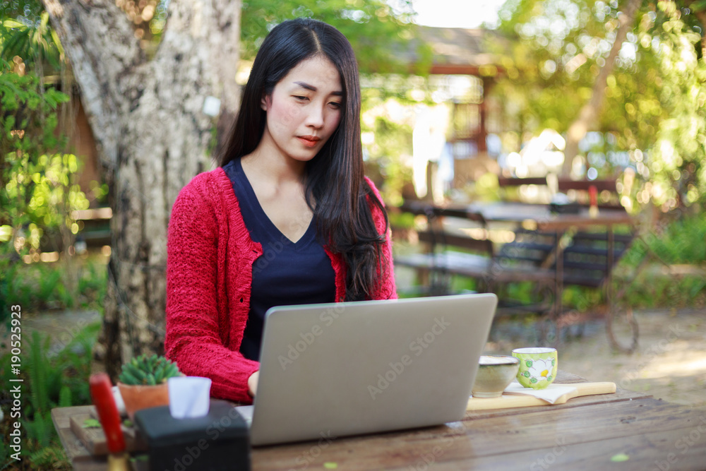 young woman using laptop and drinking coffee in garden young woman using laptop and drinking coffee in garden