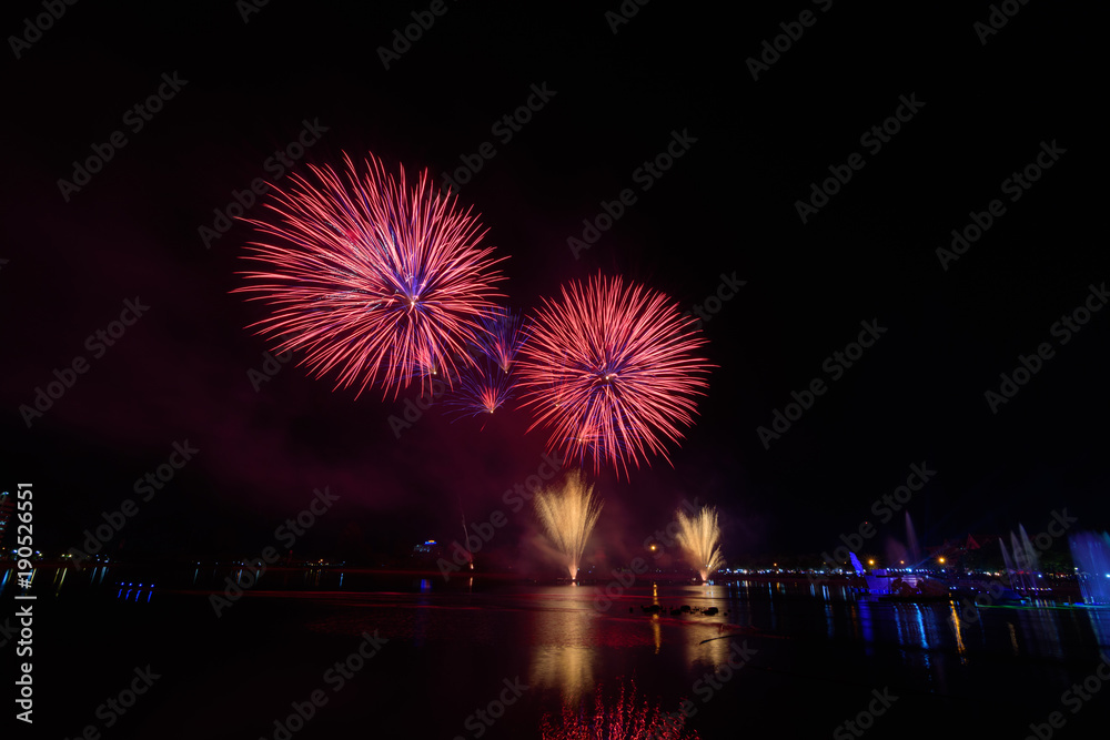 Bright and colorful fireworks against a black night sky.Fireworks for new year. Beautiful colorful fireworks display on the urban lake for celebration on dark night background.