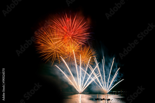 Bright and colorful fireworks against a black night sky.Fireworks for new year. Beautiful colorful fireworks display on the urban lake for celebration on dark night background.