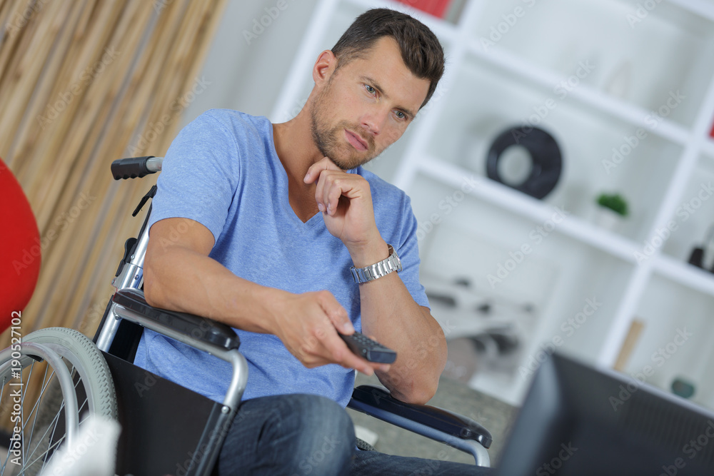 young handicapped man watching television in living room young handicapped man watching television in living room