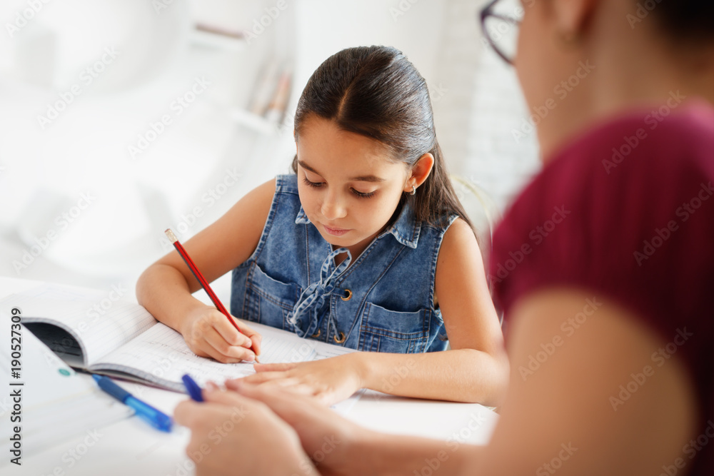 Hispanic Mother Helping Girl Doing School Homework At Home Hispanic Mother Helping Girl Doing School Homework At Home