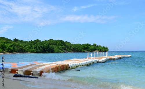 Line of plastic pier on blue sea with green island