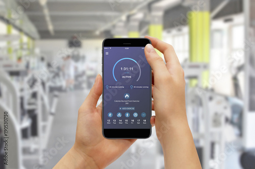 Girl checking progress with fitness app while training in gym. Fitness gadget