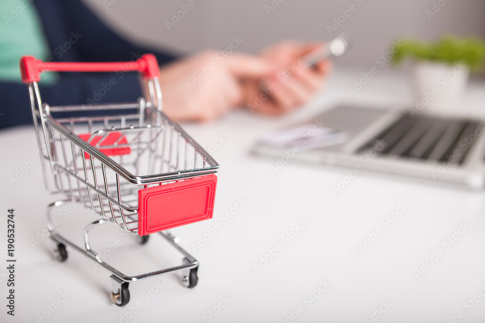  Bank card nearby a laptop and mini shopping cart on white background top view.