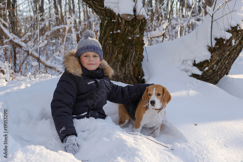 boy and Beagle dog in winter snowy forest