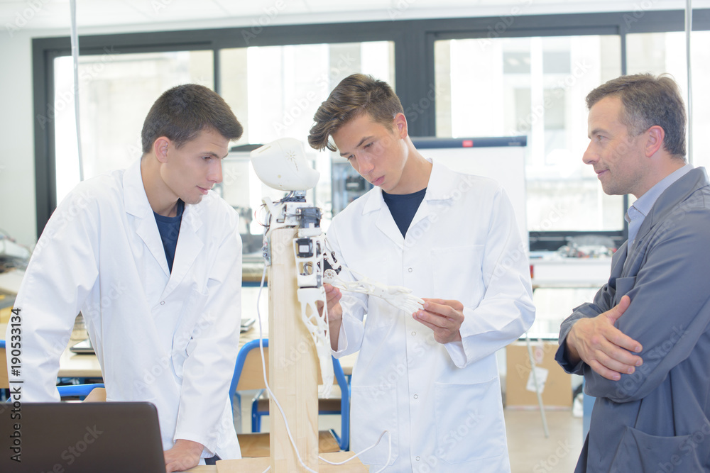 Obraz premium Teacher and students looking at robotic model