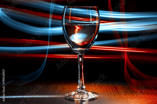 A glass of wine in a nightclub. Red and blue light effect.Blue blurred stripes.