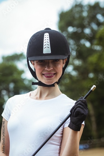 Smiling jockey with whip posing for camera 