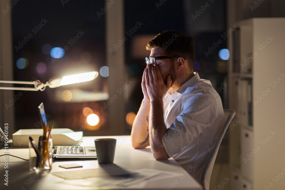 Φωτογραφία tired businessman with laptop at night office