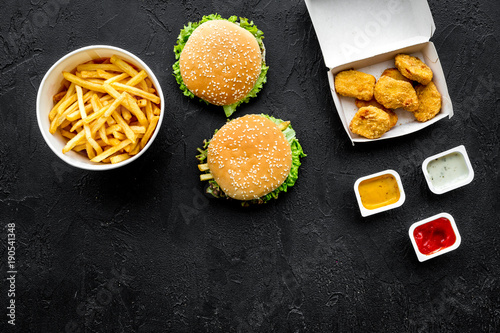 Most popular fast food meal. Chiken nuggets, burgers and french fries on black background top view copy space