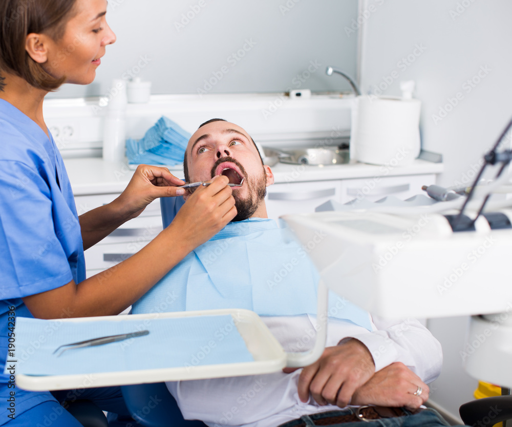 Obraz premium Dentist female in uniform is examinating of male in dental clinic