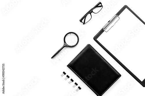 Strict monochrome white and black office desk table with pad, magnifier, notebook, glasses on white background top view copy space mock up