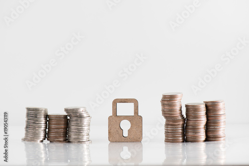 wooden lock model and coin stack illustrate financial saving, security concept