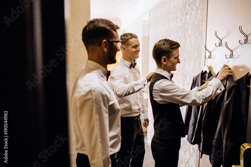 stylish groom laughing and having fun with groomsmen while getting ready in the morning for wedding ceremony. luxury man