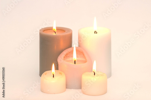 Set of five burning candles against a white background