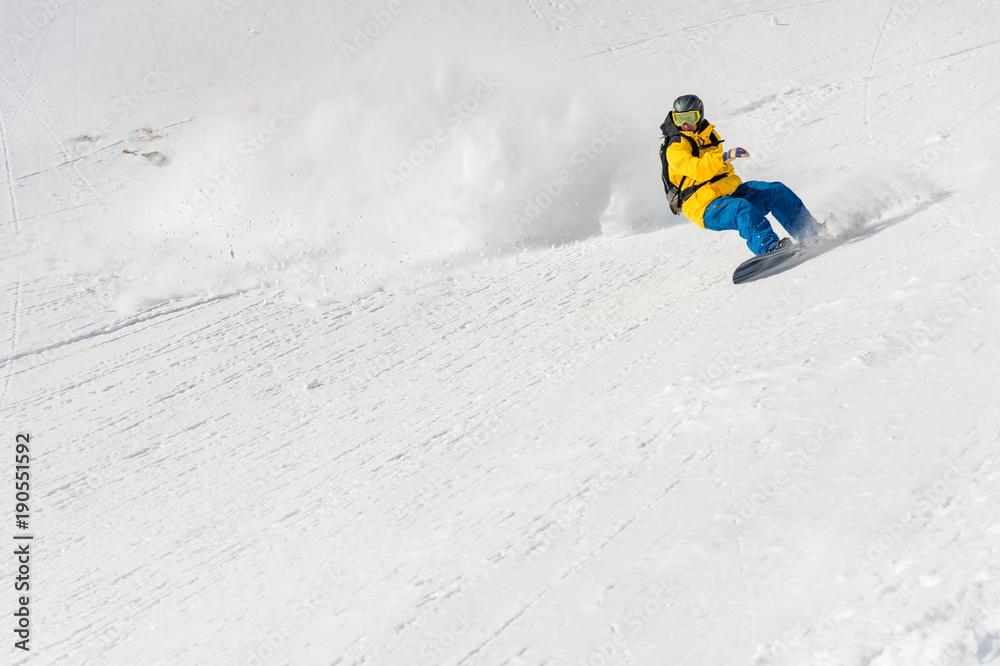 A man a snowboarder freerider descends a backcountry at high speed from a slope A man a snowboarder freerider descends a backcountry at high speed from a slope