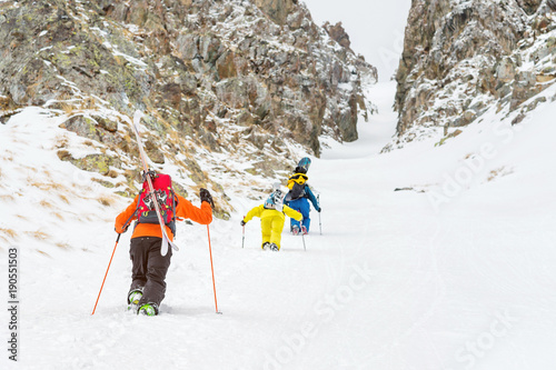 Obraz na plátně Extreme skiers climb to the top along the couloir between the rocks before the d