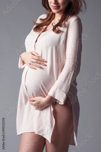 Happy smiling young pregnant woman touching her Belly. Pregnancy concept. Mom Expecting Baby. photo